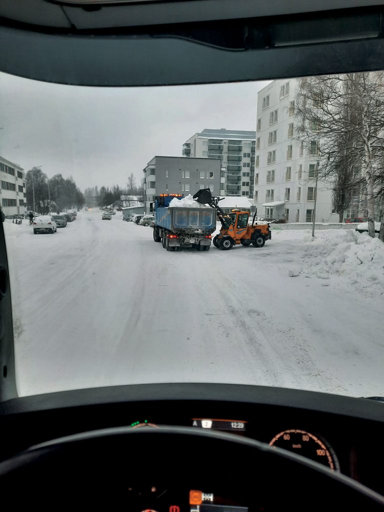 en bild av en skopa traktorn som sätter i snön i lastbilen